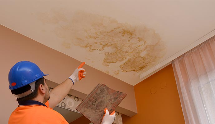 dark water spot on ceiling construction worker points to the place