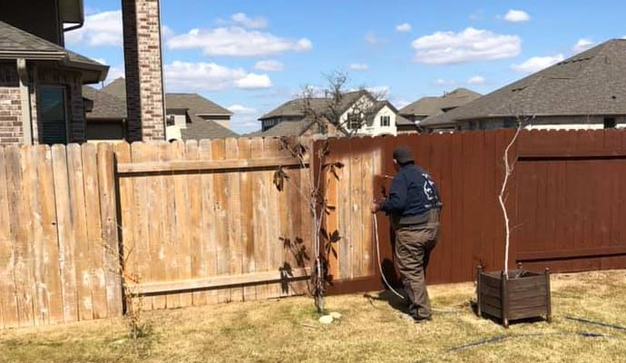 professional worker staining wooden fence
