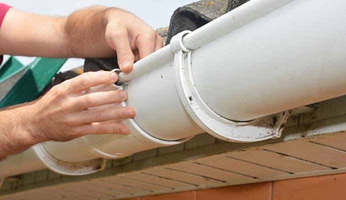Professional worker fixing gutter leak