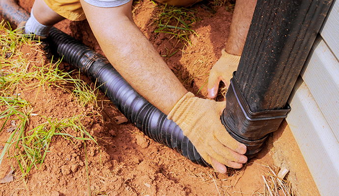 Worker installing a new downspout in a residential backyard