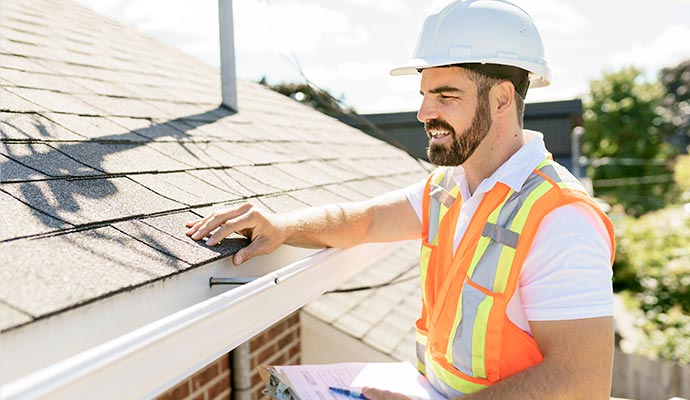 man in a hard hat holding a clipboar roof inspection and estimate