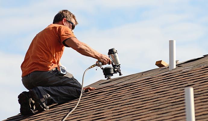 Worker performing roof maintenance using tools on a residential home
