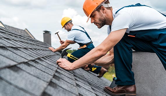 selective focus of handsome handyman repairing roof with coworker