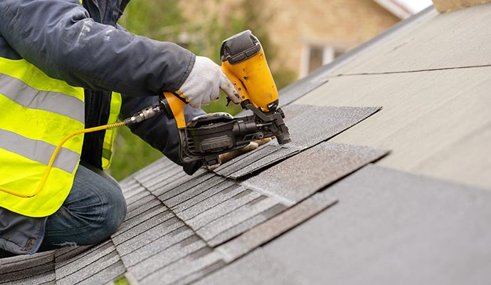 workman using pneumatic nail gun install tile on roof re-roofing service